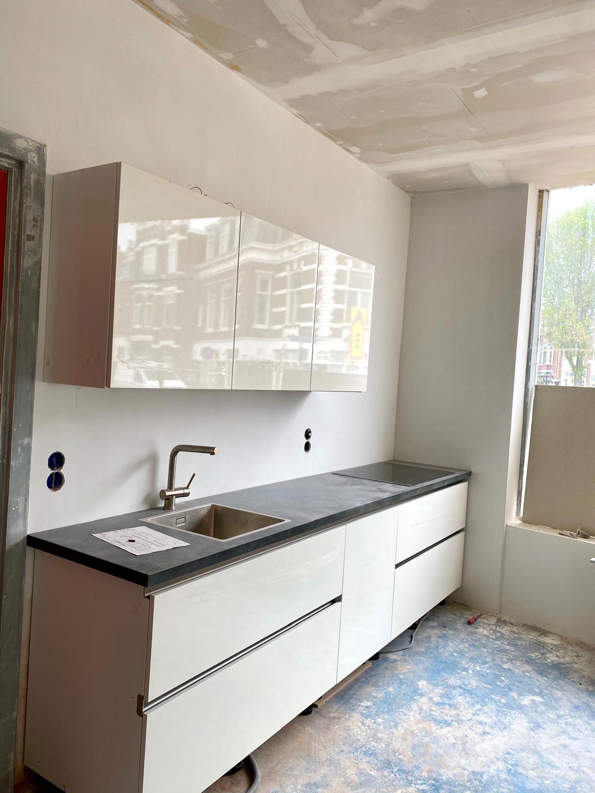 Nieuwe keuken met witte hoogglans fronten en donker werkblad